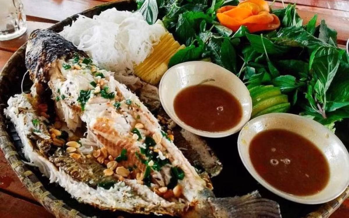Nếu gỏi tượng trưng cho sự tươi mới, thì cá lóc nướng trui lại là linh hồn của mâm giỗ quê. Cá nướng bằng rơm khô, không tẩm ướp, giữ nguyên vị ngọt tự nhiên. Khi ăn cùng bánh tráng, rau sống và nước mắm me, hương vị mộc mạc ấy khiến ai đi xa cũng bồi hồi nhớ lại hồn quê. Ảnh MIA