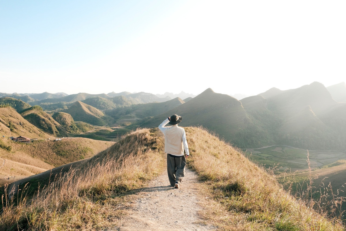 Để chạm tới điểm cao nhất của đồi – nơi có thể thu trọn khung cảnh vào tầm mắt – du khách cần đi bộ khoảng 15 phút. Con đường leo không quá khó nhưng đủ để khiến nhịp tim tăng lên đôi chút. Bù lại, khi đặt chân lên đỉnh đồi, mọi mệt mỏi dường như tan biến. Trước mắt là bức tranh thiên nhiên khoáng đạt, gió mát lành lướt qua từng triền cỏ, mang theo mùi hương ngai ngái đặc trưng của núi rừng. Ảnh Viett Anh