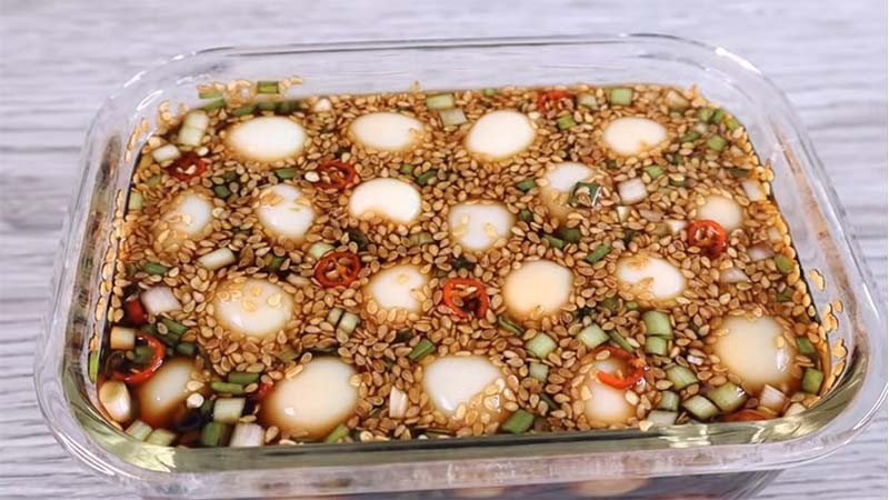 Từng “gây sốt” trên mạng xã hội, trứng lòng đào ngâm nước tương chinh phục người thưởng thức bởi vị béo mềm của trứng hòa quyện cùng nước tương đậm đà. Trứng gà được luộc vừa chín tới, bóc vỏ rồi ngâm trong hỗn hợp nước tương pha loãng với đường, chút muối và hành tây, hành lá thái nhỏ. Sau vài giờ để lạnh, trứng thấm đều gia vị, dùng kèm cơm trắng hay cháo đều rất hợp. Ảnh minh họa