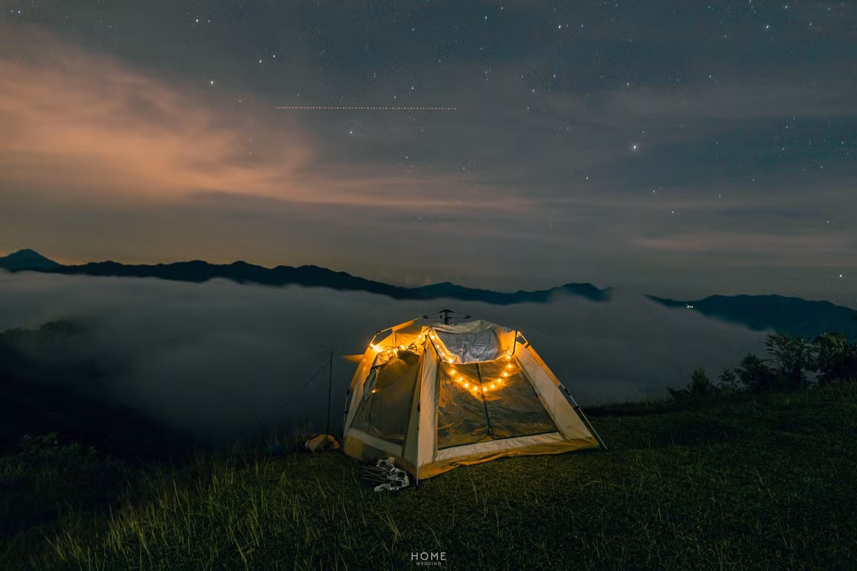 Từ đỉnh Tăk Pổ, du khách có thể phóng tầm mắt ra xa, thấy toàn cảnh bản làng nhỏ bé nằm ẩn mình trong sương. Những mái nhà sàn nằm nép bên triền núi, khói bếp buổi sớm len lỏi qua tán cây – tất cả tạo nên khung cảnh nên thơ khiến bất cứ ai cũng muốn dừng lại thật lâu để ngắm nhìn. Ảnh Nguyễn Thanh Cường