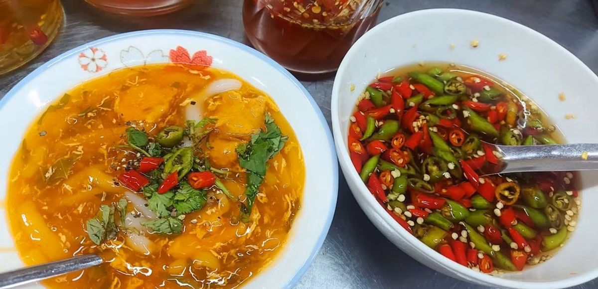 Cạnh đó, bánh canh Nam Phổ bà Vinh cũng là món không nên bỏ lỡ. Tô bánh canh có sắc đỏ cam đặc trưng từ gạch cua, nước dùng sánh đậm, sợi bánh mềm dai, điểm xuyết thêm chả và hành lá. Hương vị ngọt thanh, cay nhẹ đúng chuẩn ẩm thực xứ Huế nhưng đã được biến tấu hợp khẩu vị Đà thành. Ảnh Internet