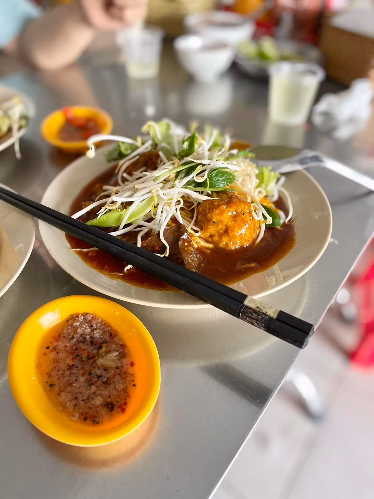 Điểm nhấn tiếp theo là phần nước sốt cà ri – “linh hồn” của món bánh. Nước sốt được nấu từ các loại gia vị như đinh hương, đại hồi, bột nghệ, quế chi, hạt mùi, ớt khô... tạo nên màu sắc đỏ au bắt mắt cùng hương thơm quyến rũ. Nồi cà ri đặt ngay trước cửa quán luôn nghi ngút khói, thơm nức, khiến thực khách khó lòng đi ngang mà không dừng bước. Ảnh Bánh tằm cay chú Đạo