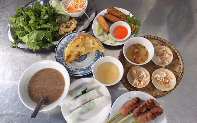 Nằm trong danh sách những món đặc trưng không thể thiếu là bánh khoái Hạnh tại đường Phó Đức Chính. Khác với bánh xèo miền Nam, bánh khoái Huế dày, giòn rụm, được chiên cùng tôm, thịt, trứng và giá. Giá trung bình khoảng 25.000 – 35.000 đồng/cái. Nhưng điểm khiến du khách nhớ mãi chính là chén nước lèo sền sệt, được pha chế từ gan heo, đậu phộng rang và tương mè – hương vị béo bùi rất riêng mà không nơi nào có được. Ảnh Foody