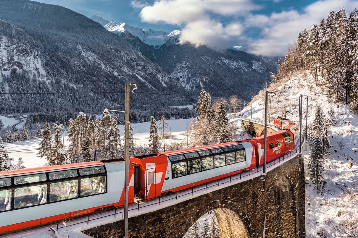 Không xa đó, Thụy Sỹ được ví như miền cổ tích giữa đời thực. Những chuyến tàu hỏa xuyên núi mang lại tầm nhìn trọn vẹn về dãy Alps, hồ nước trong xanh và những ngôi làng bình yên. Ảnh Vietravel