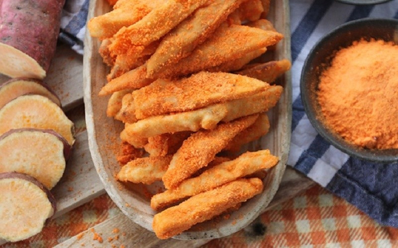 Nếu yêu thích vị béo mặn đặc trưng của phô mai, bạn khó có thể bỏ qua món khoai lang lắc phô mai. Những thanh khoai được cắt dài, chiên vàng giòn bên ngoài nhưng vẫn giữ được độ ngọt mềm bên trong. Khi còn nóng, khoai được cho vào hộp, rắc bột phô mai và lắc đều để lớp bột phủ kín từng miếng. Ảnh minh họa/ Nguồn internet