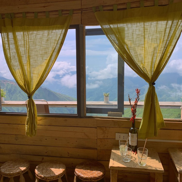 Xa trung tâm hơn một chút, Bản Coffee tọa lạc tại khu sống lưng khủng long, xã Háng Đồng – vị trí được mệnh danh là “đỉnh cao săn mây” của Tà Xùa. Từ ban công quán, toàn cảnh dãy núi trập trùng hiện ra, mây trắng quấn quanh đỉnh và ánh mặt trời dát vàng cả thung lũng phía dưới. Ảnh TapchidulichHCM