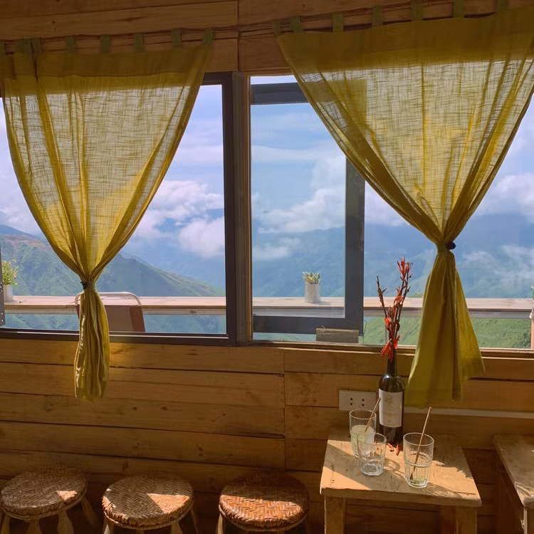 Xa trung tâm hơn một chút, Bản Coffee tọa lạc tại khu sống lưng khủng long, xã Háng Đồng – vị trí được mệnh danh là “đỉnh cao săn mây” của Tà Xùa. Từ ban công quán, toàn cảnh dãy núi trập trùng hiện ra, mây trắng quấn quanh đỉnh và ánh mặt trời dát vàng cả thung lũng phía dưới. Ảnh TapchidulichHCM