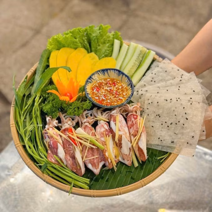 Theo tìm hiểu, mực hấp cuốn rau muống có nguồn gốc từ các vùng ven biển miền Trung như Tam Kỳ (Quảng Nam) và Đà Nẵng. Tại đây, người dân thường tận dụng rau muống biển trồng tại chỗ, mực tươi đánh bắt trong ngày, kết hợp cùng bánh tráng mè đen – loại bánh đặc trưng của miền Trung, tạo nên hương vị rất riêng biệt. Khi được ngâm mềm, bánh tráng trở nên dẻo dai, thơm bùi, làm tăng thêm sự tròn vị cho món cuốn. Ảnh Hà Nguyên