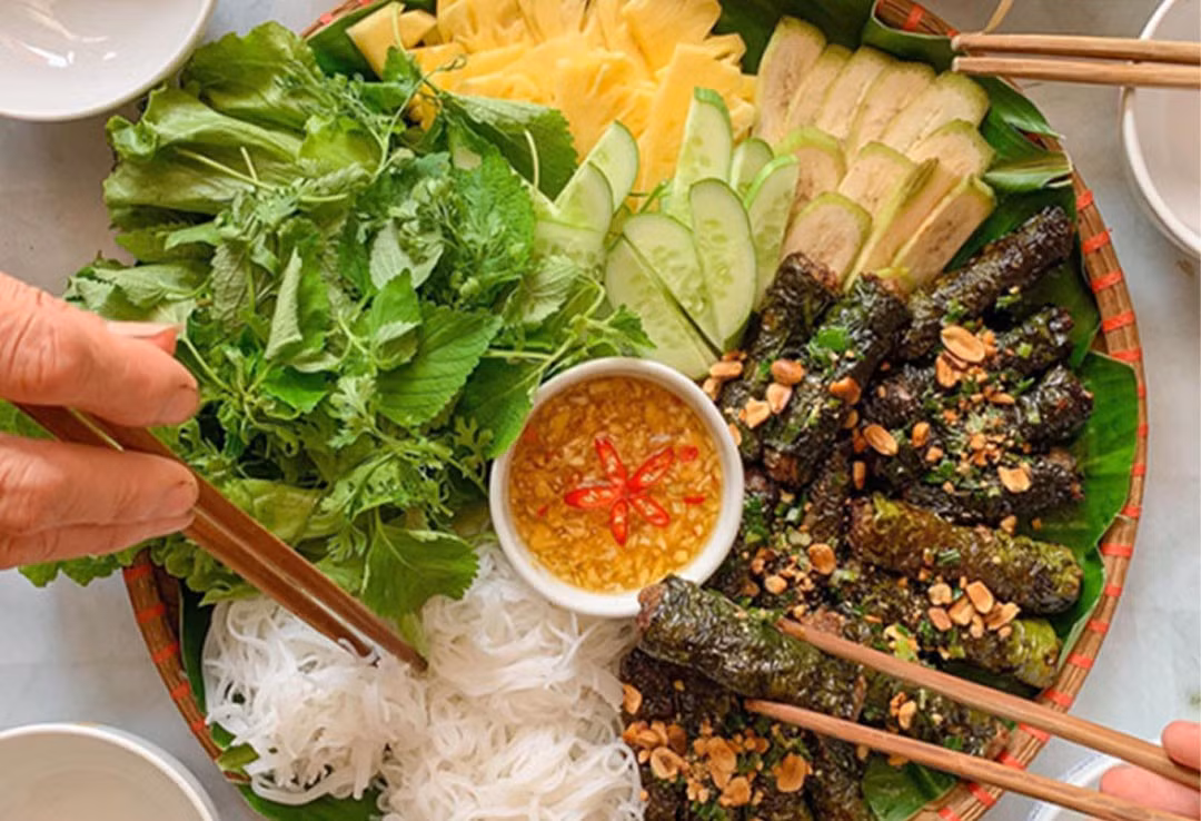 Khi phố vừa lên đèn, mùi thơm của bò cuốn lá lốt nướng trên than hồng lan tỏa khắp các con hẻm. Những cuốn bò nhỏ nhắn, được nướng chín tới, chấm cùng mắm nêm, ăn kèm bún tươi và rau sống là lựa chọn lý tưởng cho bữa xế hoặc tối nhẹ nhàng. Phố Phan Bội Châu và quanh chợ Xóm Mới là điểm đến quen thuộc của dân sành ăn. Ảnh MIA