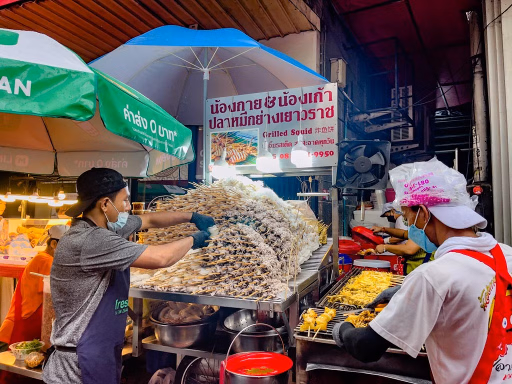 Dạo một vòng Chinatown, du khách dễ bị cuốn theo những quán ăn nhỏ nhưng nổi tiếng lâu năm. Guy Kao là điểm dừng chân quen thuộc của nhiều thực khách với món mực tươi nướng sốt cay, được bán mang đi, ăn ngay tại chỗ. Lớp mực dai ngọt tự nhiên, phủ sốt đậm vị, cay nhẹ nhưng đủ để tạo cảm giác “bắt miệng” giữa dòng người tấp nập. Ảnh laughtraveleat