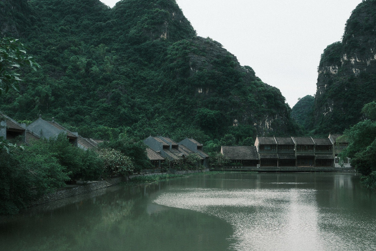 Khu vực được du khách săn đón nằm đối diện tiệm cà phê Starbucks trong quần thể Tràng An. Từ bờ gỗ ven sông, phóng tầm mắt sang phía đối diện, du khách dễ dàng bắt trọn khung cảnh dãy nhà cổ mang kiến trúc truyền thống, mái ngói trầm màu, ban công gỗ và những ô cửa sổ thẳng hàng, soi bóng xuống dòng nước xanh rêu phẳng lặng.