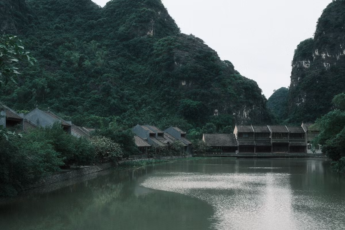 Khu vực được du khách săn đón nằm đối diện tiệm cà phê Starbucks trong quần thể Tràng An. Từ bờ gỗ ven sông, phóng tầm mắt sang phía đối diện, du khách dễ dàng bắt trọn khung cảnh dãy nhà cổ mang kiến trúc truyền thống, mái ngói trầm màu, ban công gỗ và những ô cửa sổ thẳng hàng, soi bóng xuống dòng nước xanh rêu phẳng lặng.