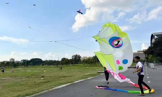 Cách trung tâm TP.HCM khoảng 15 km, bãi đất trống cạnh Trung tâm Văn hóa – Thể dục Thể thao quận 12 là điểm thả diều lý tưởng với không gian rộng rãi, gió to và tầm nhìn thoáng. Từ khoảng 16h30, nơi đây bắt đầu nhộn nhịp với các gia đình và nhóm bạn trẻ đến vui chơi, thư giãn. Ngoài thả diều, khu vực còn có sân bóng rổ, xe điện đụng và nhiều trò chơi vận động khác dành cho trẻ em, tạo nên một không gian sinh hoạt cộng đồng sôi động vào mỗi buổi chiều. Ảnh Hà Phương