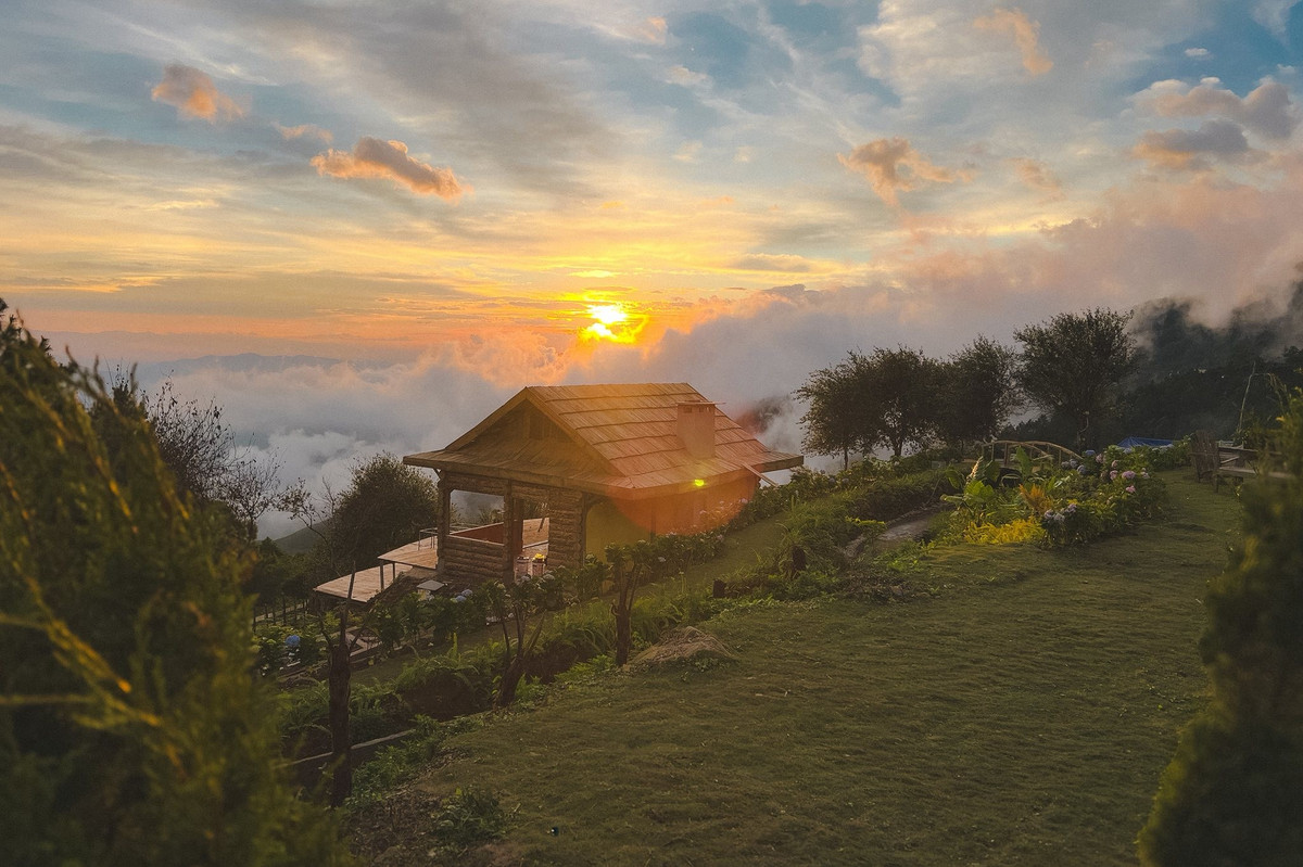 Giữa không khí bảng lảng của vùng núi Sơn La, mặt trời lặn chậm rãi sau lớp mây, để lại những vệt sáng đỏ rực hắt lên đường chân trời. Vào ngày thời tiết thuận lợi, biển mây dày đặc, chuyển động nhẹ như suối trắng trôi lững lờ, tạo nên khung cảnh lãng mạn khó diễn tả bằng lời. Ảnh Tiệm cà phê Hoàng Hôn-Khe Cải Tà Xùa