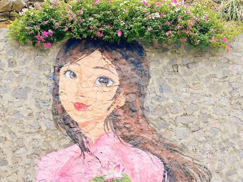 Để có bức hình ưng ý bên tranh vẽ, du khách nên chọn trang phục nhẹ nhàng, nữ tính như váy trắng, váy tím nhạt, áo dài hiện đại hoặc đầm maxi. Nam giới có thể mặc sơ mi trắng, quần sáng màu và sneaker nhẹ. Kính râm, mũ rộng vành, giỏ mây và tripod mini sẽ giúp bạn có những bức ảnh ấn tượng. Thời gian chụp ảnh đẹp nhất là sáng từ 07:30 đến 09:30 hoặc chiều từ 15:30 đến 17:00 – khi nắng vừa đủ, ánh sáng mềm và bầu trời trong xanh. Ảnh Huyền Khánh Vũ