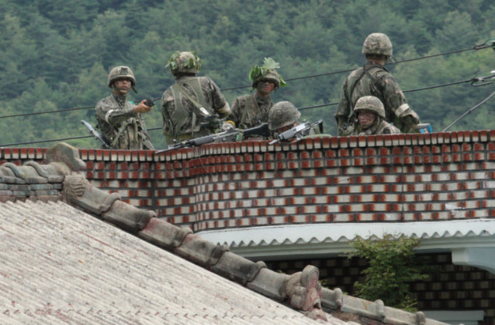 Các binh sĩ Hàn Quốc trên nóc nhà bao vây binh sĩ Yim. Đấu súng đã nổ ra giữa 2 bên.