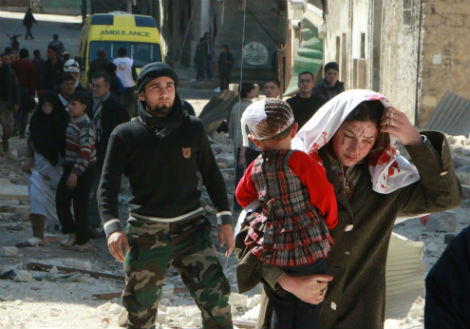 Một người phụ nữ Syria đang mang bế đứa trẻ sau một cuộc không kích của quân chính phủ Syria ở Aleppo vào ngày 15/3/2014.
