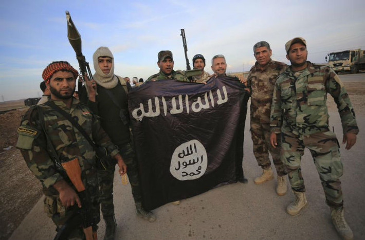 Quân nhân Iraq chụp ảnh bên cạnh một lá cờ của IS.