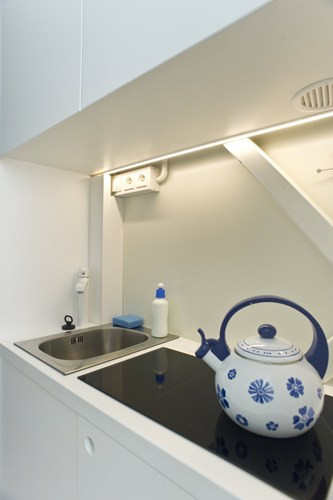 Tầng một của nhà bao gồm một nhà vệ sinh có vòi hoa sen, một bếp căn với chậu rửa và tủ chè, một chiếc bàn cho 2 người và ghế hạt xốp.
