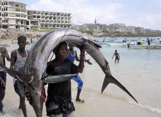 Nam thanh niên người Somalia vác con cá “khủng” trên đầu gần bờ biển Ấn Độ Dương tại Mogadishu.