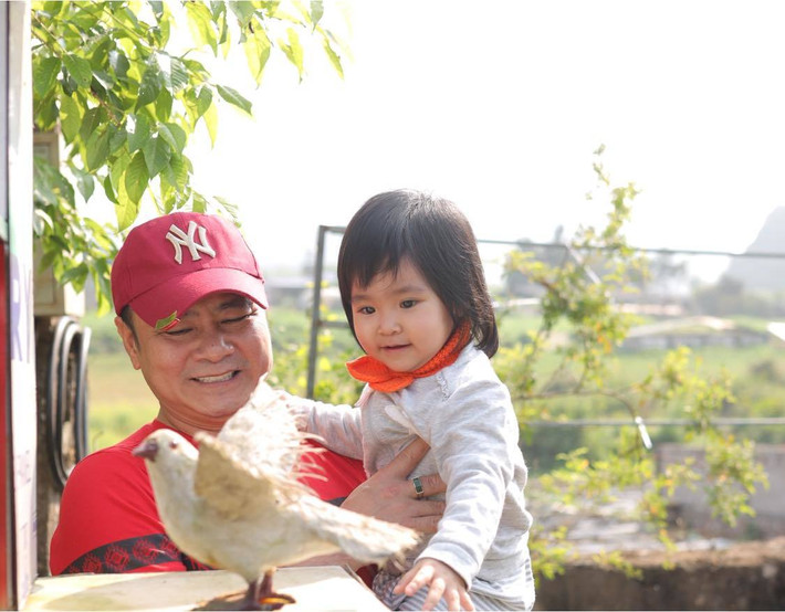 Tự Long cùng con gái thứ 2 chơi đùa ngoài sân nắng.