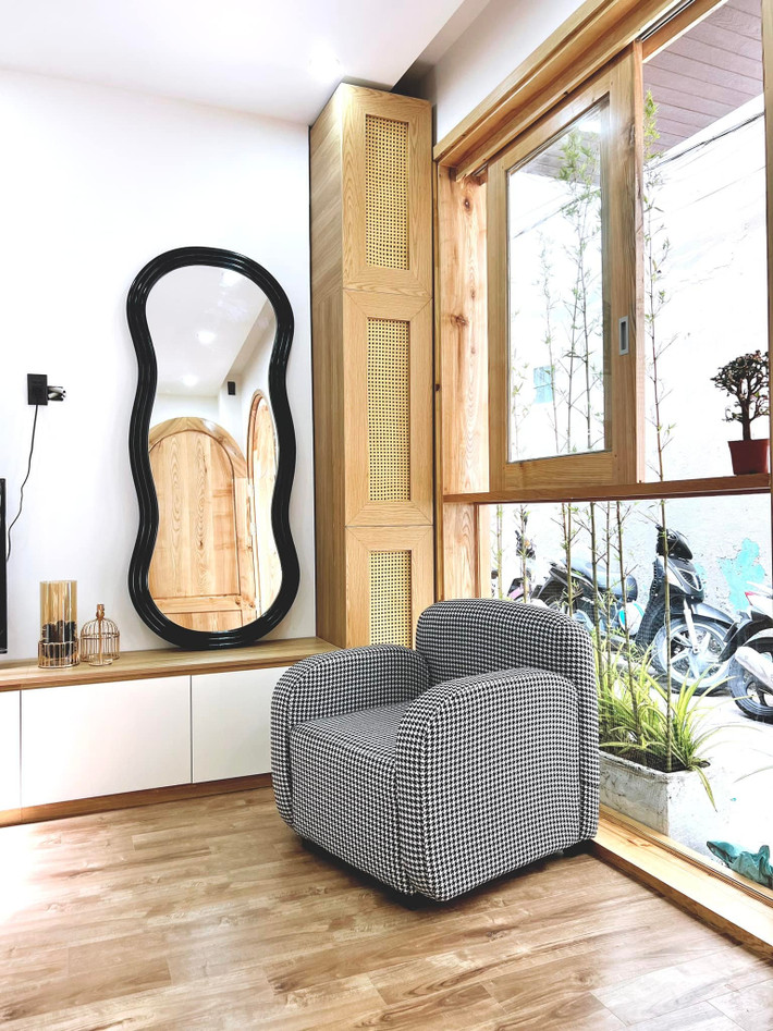 Ghế sofa đơn đọc sách bên cửa sổ kính lớn, mở rộng tầm mắt ra ngoài đường. Góc tủ tivi chị Sony Trương đặt 1 cây thần tài núi để lọc không khí và tạo mảng xanh cho nhà.