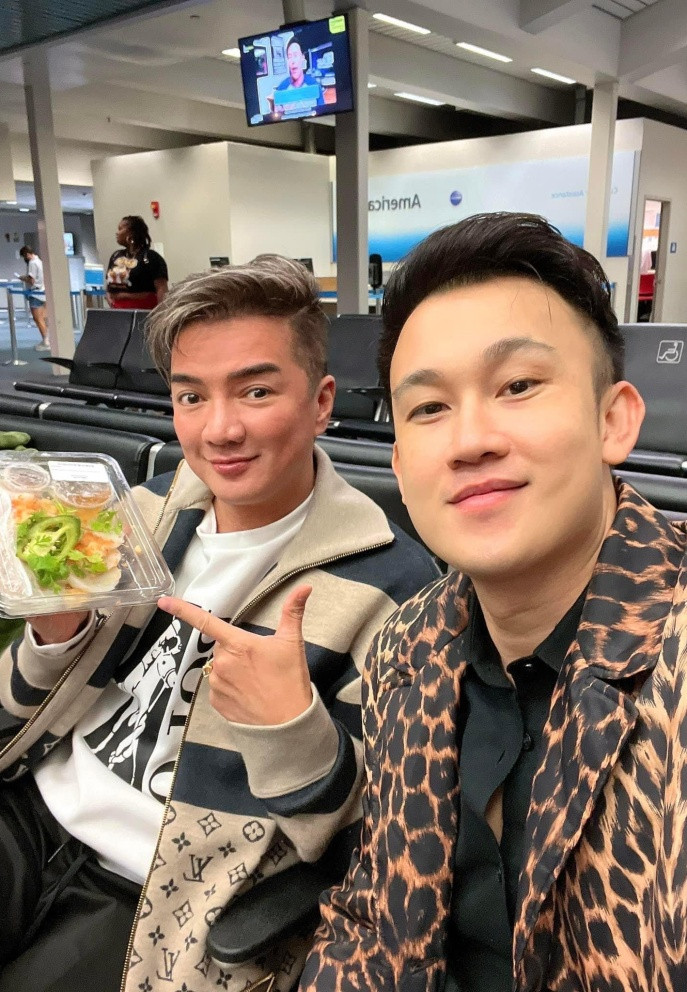 Đàm Vĩnh Hưng và Dương Triệu Vũ tranh thủ "chống đói" với hộp bánh bèo trước giờ bay.