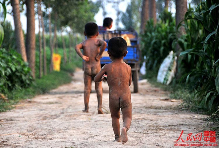 Hai đứa trẻ trong những bức hình này phải sống tách biệt với bố mẹ. Chúng trần truồng, chạy nhảy, chơi đùa trên con đường làng bụi bặm.