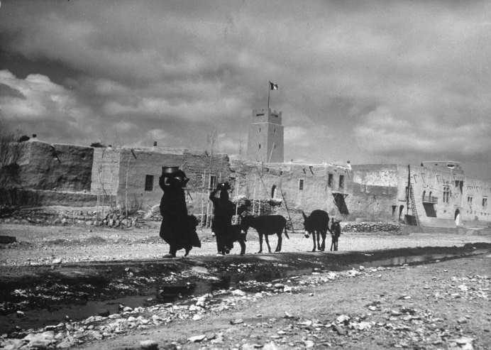 Hai người phụ nữ Syria đội chậu chứa nước trên đầu. Đi đằng sau họ là những con la. Tấm ảnh này được chụp tại một con đường thuộc ngôi làng gần Damascus, Syria năm 1940.