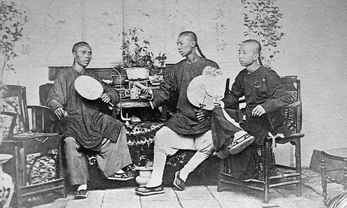 Ba người đàn ông Trung Quốc trong trang phục truyền thống, tóc tết đuôi sam, ngồi trò chuyện với nhau.