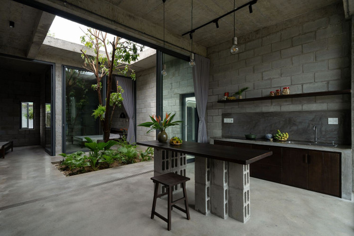 Cửa kính lớn mở ra khu vườn, làm mờ ranh giới giữa trong nhà và ngoài trời, tạo ra một môi trường yên tĩnh, hòa mình vào thiên nhiên.