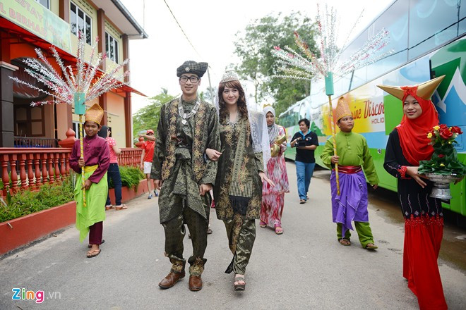 Đoàn rước dâu gồm những thanh niên trong trang phục truyền thống bưng cờ hoa, chiêng trống đưa cặp đôi từ đầu làng vào toà nhà chính. "Vợ" của JVevermind trong đám cưới là một nữ diễn viên, ca sĩ trẻ người Thái Lan - Ying Kanyapatch. Cô cũng từng đoạt giải nhất Miss Teen Thailand 2007.