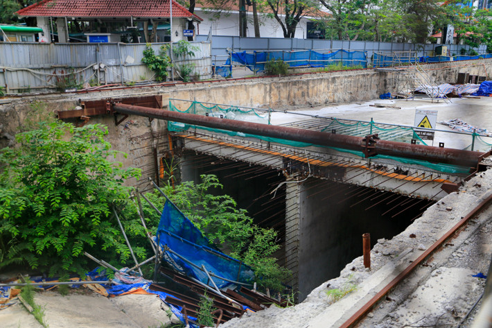 Bên trong công trường một số giàn giáo sập xuống hố, vật liệu chất thành đống, có dại mọc um tùm không có ai dọn dẹp.
