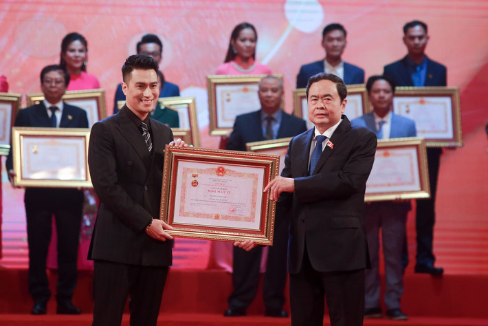 Diễn viên Việt Anh nở nụ cười rạng rỡ khi được nhận danh hiệu Nghệ sĩ Ưu tú từ tay Phó Chủ tịch Quốc hội Trần Thanh Mẫn.