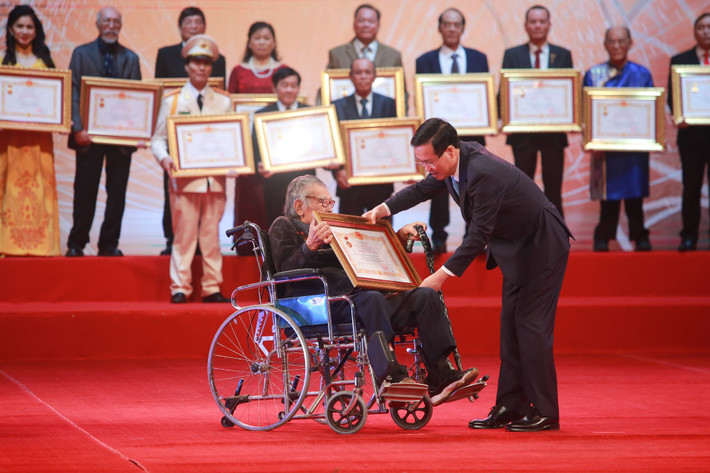 Nghệ sĩ Hoàng Qân Tạo - nguyên Giám đốc Nhà hát Kịch Hà Nội di chuyển bằng xe lăn đến nhận danh hiệu Nghệ sĩ Nhân dân cao quý.