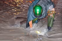 Hình ảnh thượng sĩ công an móc rác giúp đường thoát ngập