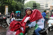 Xúc động cha mẹ đội mưa đưa con đi làm thủ tục dự thi