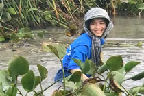 Nữ sinh cười rạng rỡ, ngâm mình dọn rác dưới đầm nước