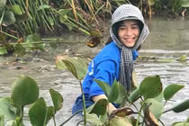 Nữ sinh cười rạng rỡ, ngâm mình dọn rác dưới đầm nước