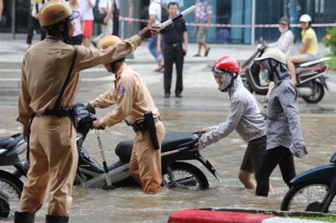 Khu vực trước tòa nhà Keangnam, các chiến sĩ Đội CSGT số 6 hỗ trợ, dắt xe cho người dân đi qua khu ngập lụt. Ảnh: GDVN