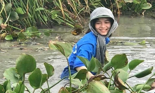 Nữ sinh cười rạng rỡ, ngâm mình dọn rác dưới đầm nước