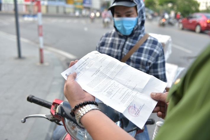 Anh Nguyễn Đắc Cường - nhân viên giao hàng của một công ty đóng trên địa bàn quận Đống Đa xuất trình giấy xác nhận điều động của công ty cho lực lượng chức năng kiểm tra.