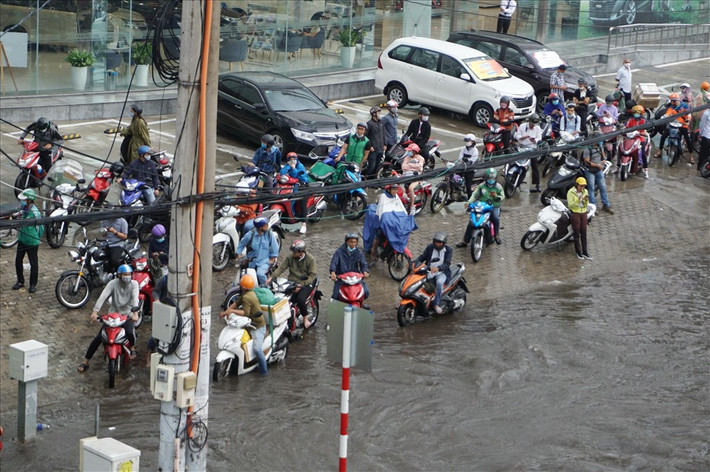 Đường ngập sâu, hàng loạt phương tiện phải dừng lại trên vỉa hè chờ nước rút mới có thể di chuyển tiếp.