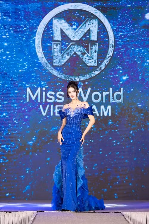 Về đầm dạ hội cho chung kết, trước khi đi thi, người đẹp công bố hai mẫu váy dạ hội dành cho chung kết. Bộ đầm màu xanh mang tên Aurora of the sea của NTK Hoàng Tony lấy cảm hứng từ hiện tượng cực quang hiếm gặp trên biển – nơi sóng nước giao hòa cùng bầu trời tạo nên những vệt sáng kỳ ảo. Thiết kế trễ vai vừa gợi cảm vừa sang trọng được đính kết tỉ mỉ. Phần tà váy được xử lý xếp tầng mềm mại, gợn sóng uyển chuyển. Ảnh: FB Ý Nhi.