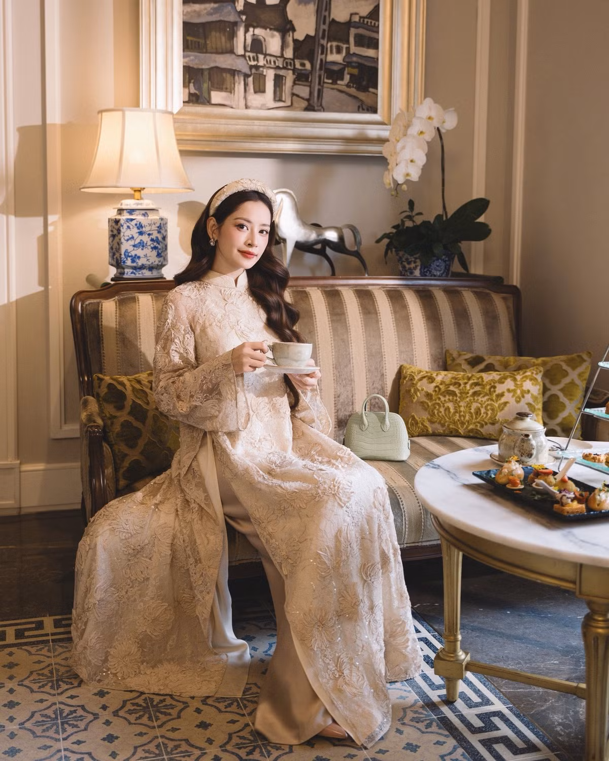 Chi Pu chọn áo dài màu kem với chất liệu ren hoa nổi, kết hợp chi tiết đính kết tinh tế, tạo nên vẻ ngoài vừa nữ tính vừa sang trọng. Ảnh: FB Chi Pu.