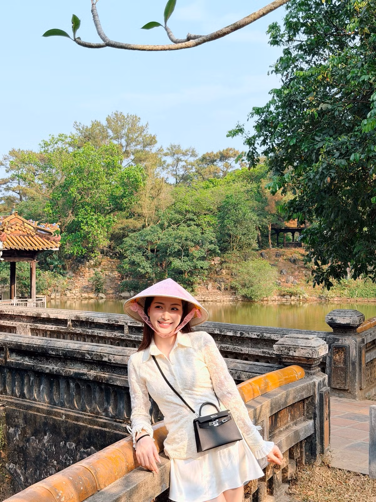 Cô xuất hiện với vẻ ngoài nữ tính trong set đồ ren trắng, kết hợp cùng nón lá hồng và túi xách đen.