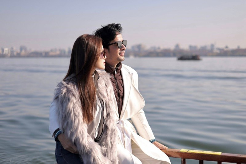 Đôi vợ chồng son xuất hiện tình tứ bên bờ sông. Cả hai diện trang phục ấm áp. Ảnh: FB Đoàn Minh Tài.