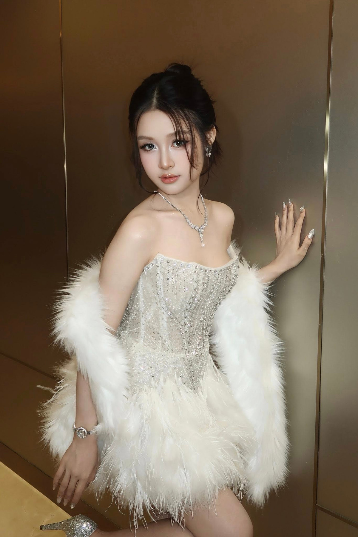 Nữ diễn viên sinh năm 2008 diện váy dạ hội dáng corset đính kết lấp lánh, ôm trọn vóc dáng thon gọn, kết hợp áo choàng lông trắng mang lại cảm giác kiêu sa.