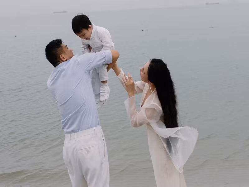 Chồng Hồ Quỳnh Hương bồng bế con trai cưng trên bãi biển. Ảnh: FB Hồ Quỳnh Hương.