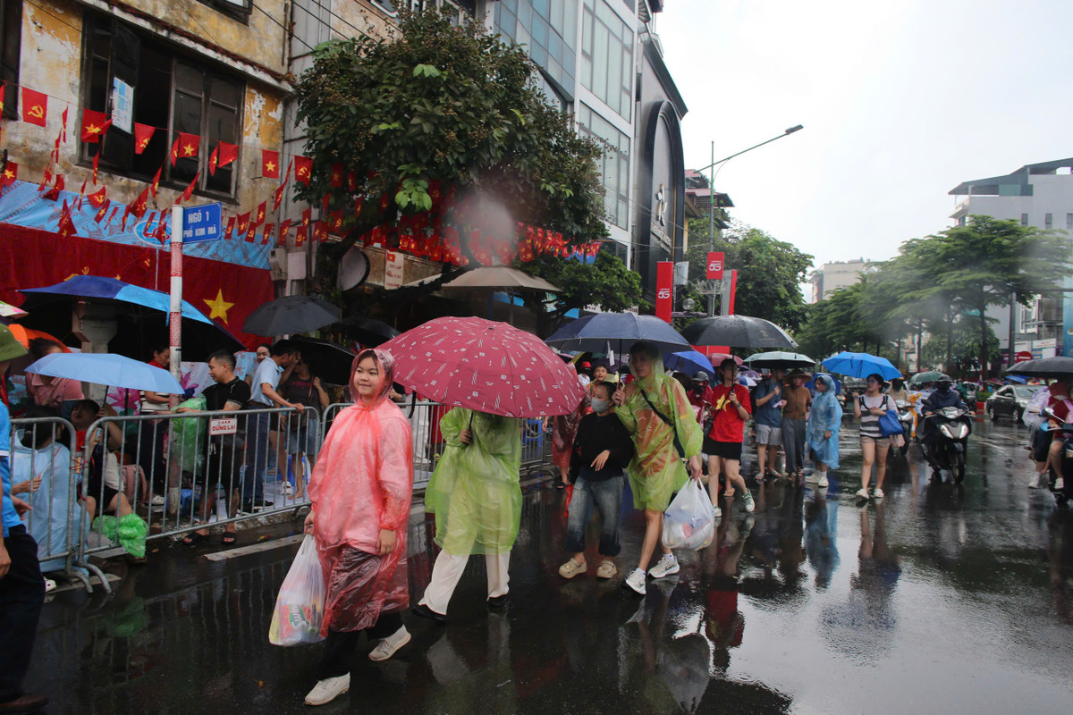 Nhiều người đội mưa đi tìm chỗ xem diễu binh.